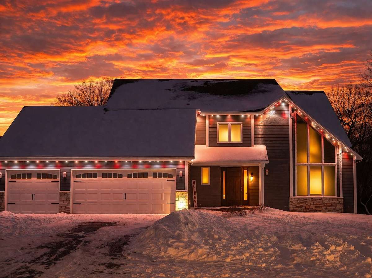 Craftsman home with Christmas lights at dramatic sunset